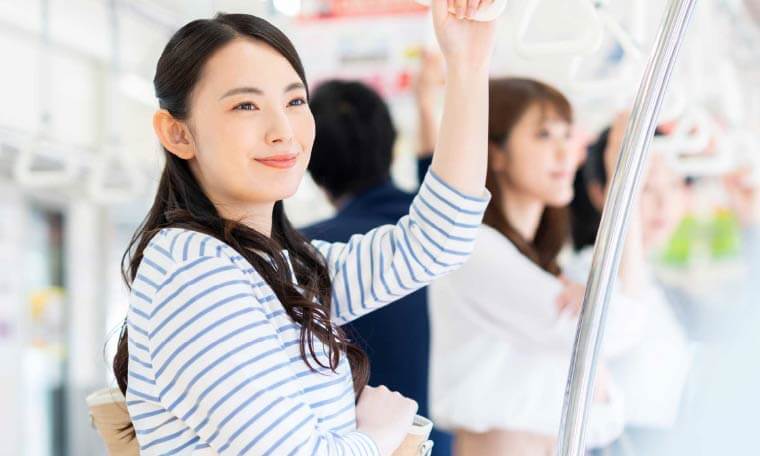 電車内で吊り革を持って微笑む女性